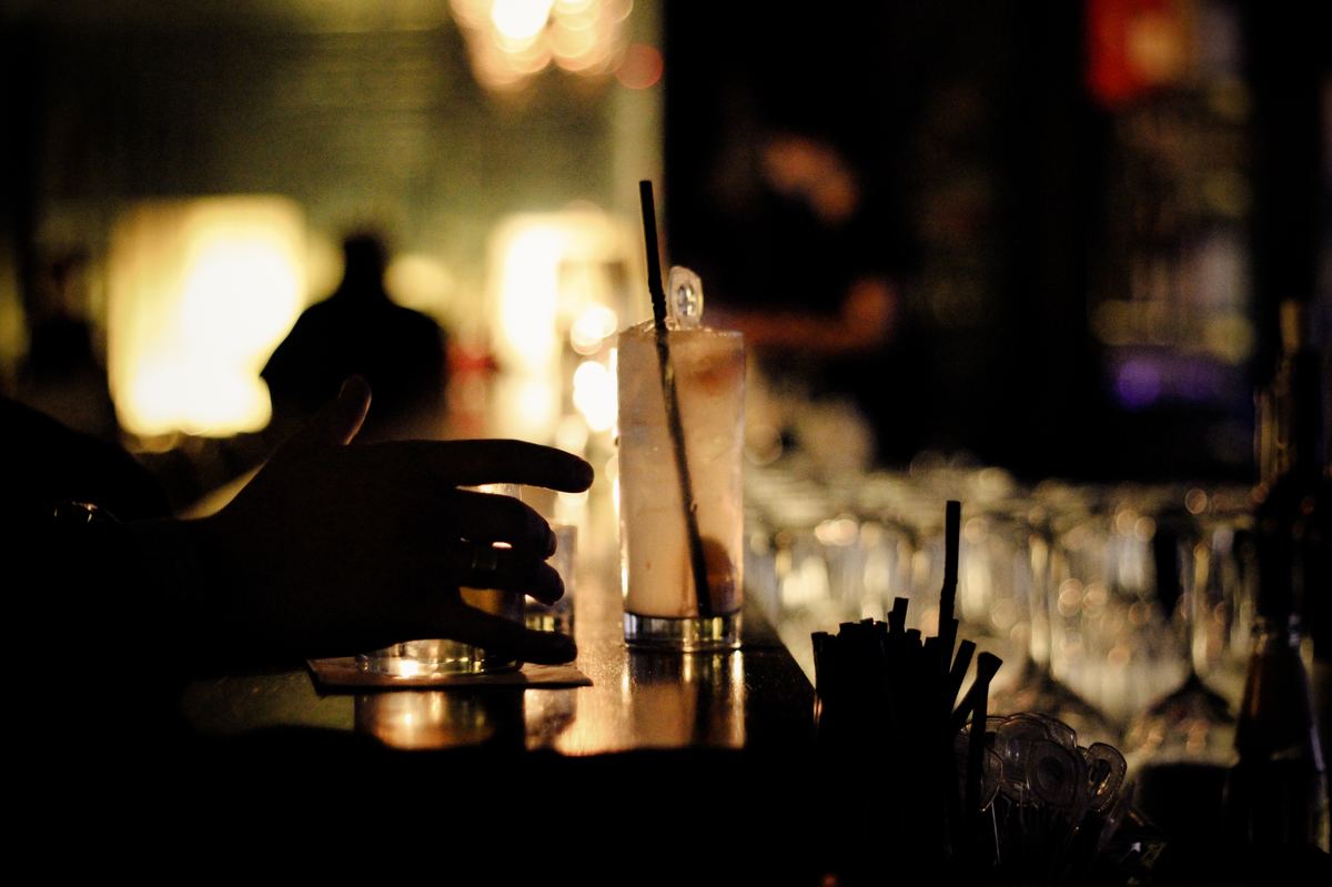 A tall drink on a dark timber bar counter in low light