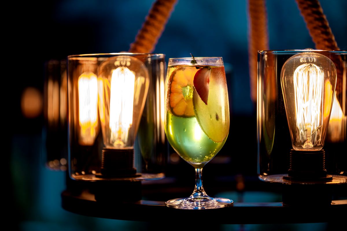 A bright cocktail with fresh fruit, framed by warm Edison-bulb light